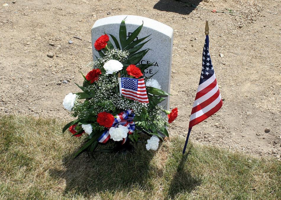 Flowers and american flags at gravestone