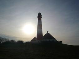 evening photo of a striped lighthouse on the North Sea coast