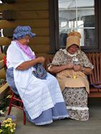 two senior Women in vintage Costumes Knitting