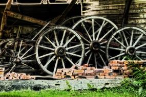 Beautiful, old wheels among the bricks, near the green grass