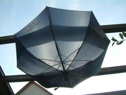 Beautiful, black, transparent umbrella on the construction, in light, under the blue sky with clouds