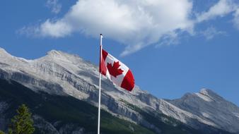 Red and white flag of Canada, with the maple leaf, among the beautiful mountains