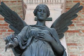 statue of an angel on a cross in a cemetery