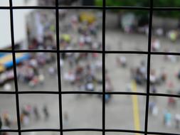 View of the street, with the people, through the wire mesh