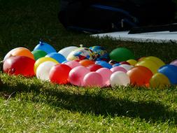 Colorful balloons with water, on the green grass, in light and shadow