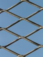 Close-up of the shiny metal fence, at blue sky on background