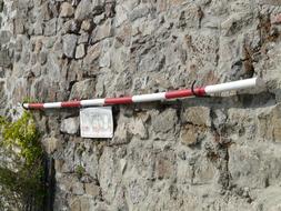 Red and white rescue rod on the stone wall, with the colorful plants