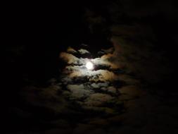 moon through thick clouds in the night sky