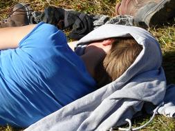 Person, sleeping in the cloth, on the colorful grass, in light and shadow