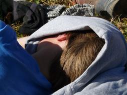 Person, covered in the clothing, resting on the colorful grass