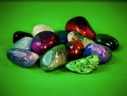Close-up of the pile of the beautiful and colorful, shiny gemstones, on the green surface