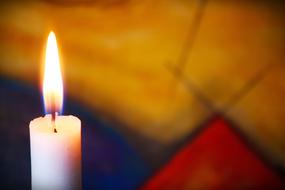 white candle burns at blur background