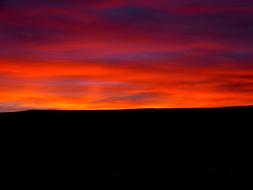 Sunrise, Red and purple Clouds above dark land