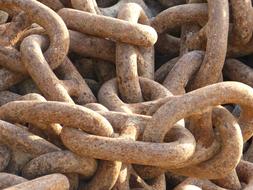 Close-up of the rusty, iron chain in light