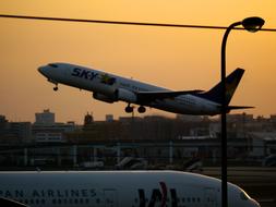 Airplane, taking off from the airport, at beautiful and colorful sunset