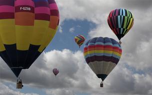 Flying, colorful, patterned hot air balloons in the blue sky with clouds