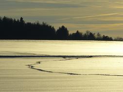 narrow path on snowy frozen lake at evening