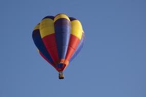 Colorful, flying gas filled balloon, in the beautiful, blue sky