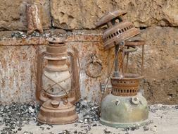 Old, rusted, metal kerosene lamp, near the stone wall