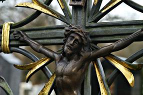 bronze sculpture of crucified Jesus in the cemetery close-up on blurred background