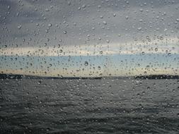 splashing rain on the window against the background of the sea