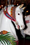 Colorful, patterned, shiny horses at the carousel horse among the darkness