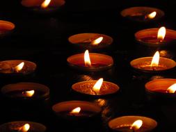 Close-up of the beautiful, burning tea lights, among the darkness