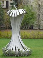 Sculpture of the apple stub on the green grass, among the colorful plants