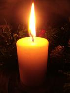 Close-up of the beautiful and colorful, burning Christmas candle, among the darkness