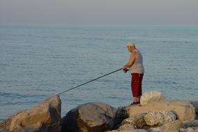 lonely fisherman on a rock near the sea