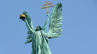 Archangel with cross, in sunlight, under the blue sky, on the Heroes' Square in Budapest, Hungary