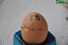 Close-up of the egg with broken shell and drawn face, on the stand