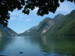 Beautiful landscape of the KÃ¶nigsee lake with birds, among the mountains with plants, in Germany, under the blue sky with clouds