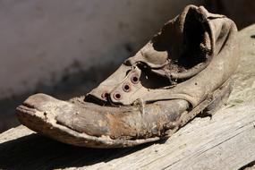 Damaged Dirty Old menâs shoe on wooden bar