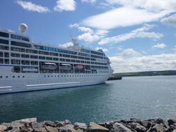 Cruise vessel in the harbor of Scotland, with rocks, under the blue sky with white clouds