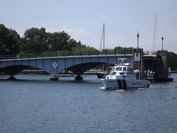 Police boat in the water, near the bridge, near the colorful plants