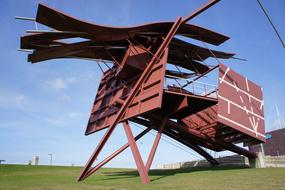 Rusty, steel construction, on the green meadow, under the blue sky with clouds