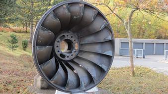 Close-up of the turbine wheel near the building, among the colorful plants