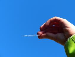 Person holding shiny icicle in the hand in sunlight, under the blue sky