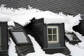 Roof of the house with windows, in snow, in the winter