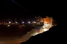 Open pit mining of brown coal, with bucket wheel excavators, on landscape with lights, at the night