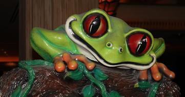 Colorful, cute and shiny sculpture of the frog on the tree