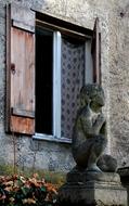 Statue near the colorful plants and open window of the building, in Munich, Germany