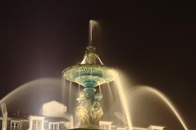 Beautiful fountain near the buildings in Lisbon, Portugal, at the night