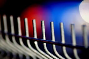 Close-up of the fence in light, at background with colorful bokeh lights