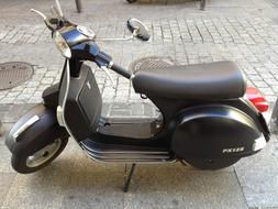 Black scooter on the street, near the pavement
