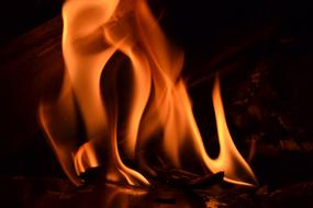 Close-up of the colorful flames in fireplace, among the darkness, at the night