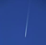 white trail from an airplane in a bright blue sky