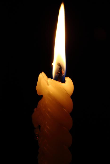 Beautiful candle with bright fire, at black background