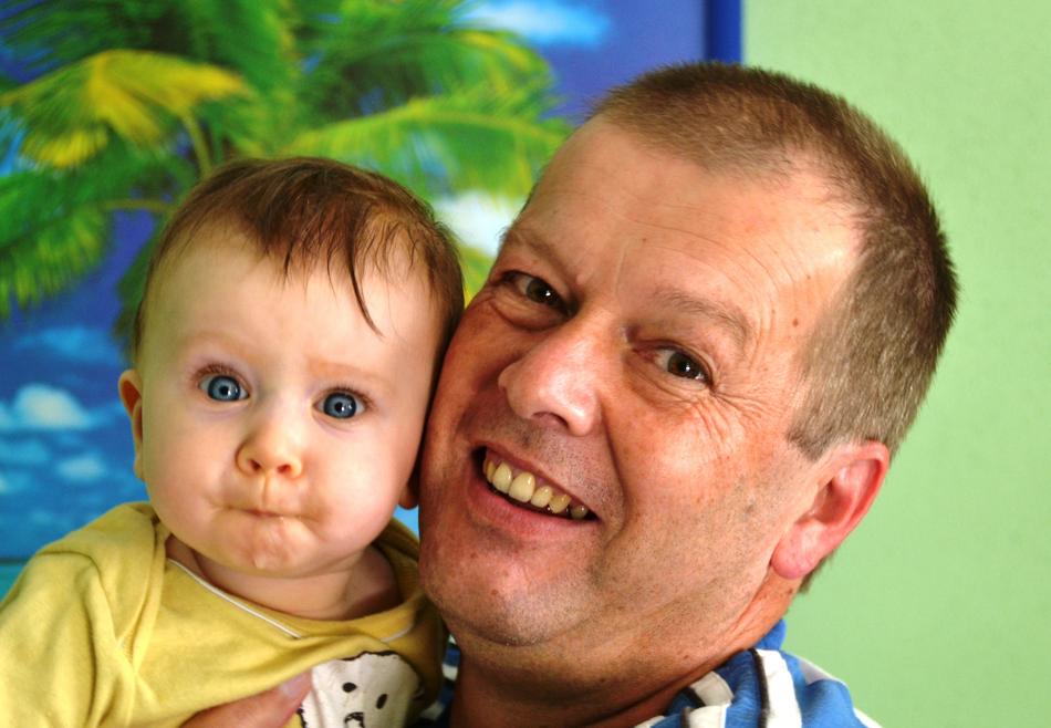 Portrait of the smiling grandpa and grandson, near the green and yellow plant